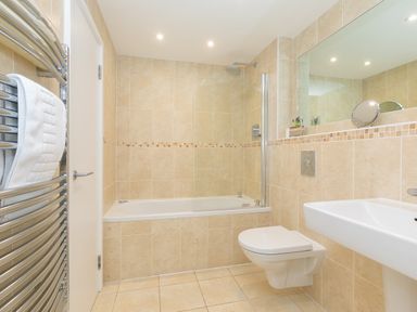 A bathroom with a bathtub shower toilet sink and towel rack at Portside in Carbis Bay