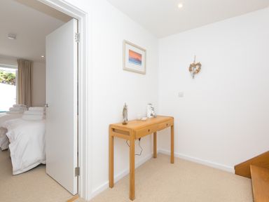 A hallway with a wooden table and decorations next to a door leading to a bedroom at Portside in Carbis Bay
