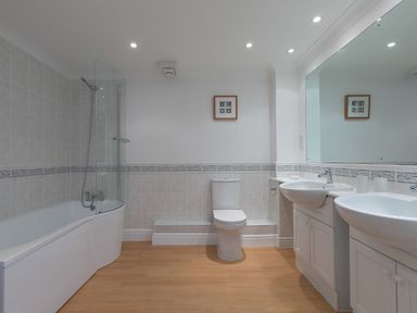 A bathroom with a bathtub shower combination toilet double sink and large mirror at Sapphire in Carbis Bay