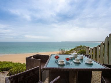 A patio table with tea set and bowls of strawberries overlooking a sandy beach and ocean at Sapphire in Carbis Bay