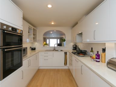 A kitchen with white cabinets and appliances including an oven microwave and stove at Sapphire in Carbis Bay