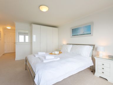 A bedroom with a bed white bedding side tables lamps and a wardrobe at Sapphire in Carbis Bay