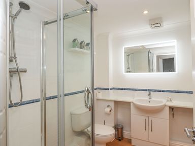 A bathroom with a shower enclosure toilet sink and illuminated mirror at Sapphire in Carbis Bay