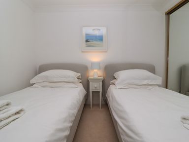 A bedroom with two single beds separated by a bedside table with a lamp and a framed picture on the wall at Sapphire in Carbis Bay