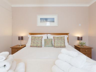 A bedroom with a double bed with three embroidered cushions and two bedside tables with lamps at Seathrift in Carbis Bay