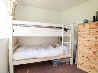 A bedroom with a white bunk bed and a wooden dresser at Chalet 150 in Winterton-On-Sea