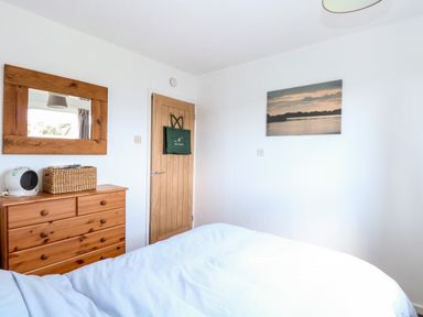 A bedroom with a wooden dresser mirror and wooden door with a bag hanging at Chalet 150 in Winterton-On-Sea