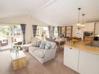 A living room with sofa armchair dining table and kitchen area at Seagull Lodge in Runswick Bay