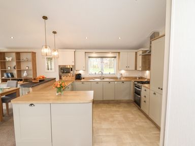 A kitchen with cabinets sink stove microwave and a dining area at Seagull Lodge in Runswick Bay