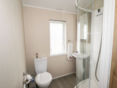 A bathroom with a toilet window sink towel and shower at Seagull Lodge in Runswick Bay