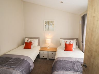 A bedroom with two single beds and a nightstand with a lamp at Seagull Lodge in Runswick Bay
