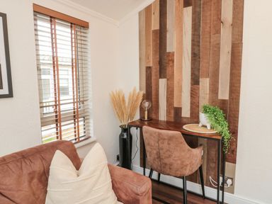 A corner with a wooden desk and chair near a window with wooden blinds at Woodland View Lodge Swarland near Felton