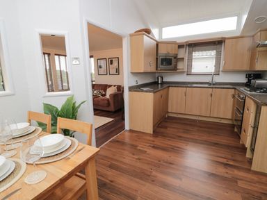 A kitchen with wooden cabinets and a dining table set with plates and glasses at Woodland View Lodge Swarland near Felton