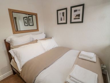 A bedroom with a double bed made with white and beige linens and two towels on the bed at Woodland View Lodge Swarland near Felton