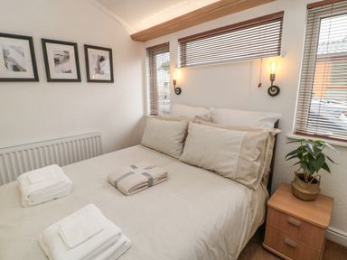 A bedroom with a bed and towels on it a nightstand with a plant and three framed pictures on the wall at Woodland View Lodge in Swarland near Felton
