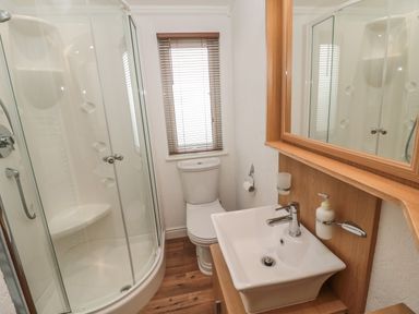 A bathroom with a shower enclosure toilet sink and mirror at Woodland View Lodge in Swarland near Felton