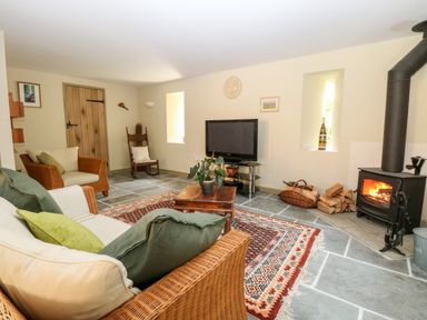 A living room with sofas a wooden coffee table a television and a wood burning stove at The Hermitage West Beckham near Sheringham