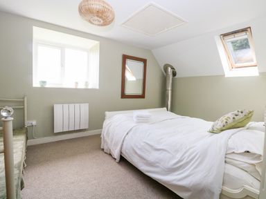A bedroom with a double bed mirror and windows at The Hermitage in West Beckham near Sheringham