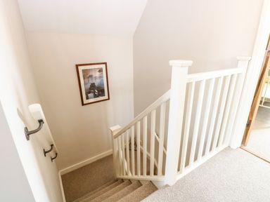 A staircase with white railings and beige carpet with a framed picture on the wall at The Hermitage in West Beckham near Sheringham