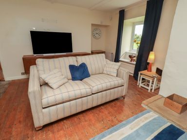 A living room with a sofa and television at ASTA COTTAGE in Cresswell