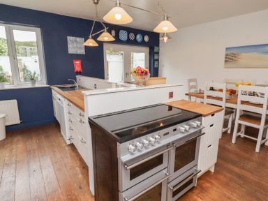 A kitchen with stove and seating area at ASTA COTTAGE in Cresswell