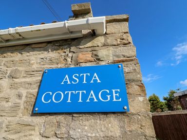 A sign on a stone wall at ASTA COTTAGE in Cresswell