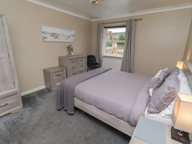 A bedroom with a bed, nightstand, and dresser at ASTA COTTAGE in Cresswell