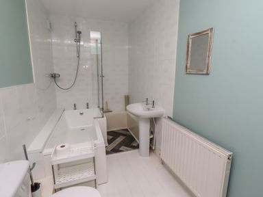 A bathroom with a bathtub, shower, toilet and sink at ASTA COTTAGE in Cresswell