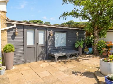 A garden view featuring a cabin with a bench and planters at ASTA COTTAGE Cresswell