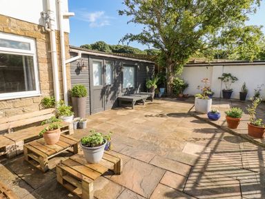 A garden area with patio and planters at ASTA COTTAGE in Cresswell