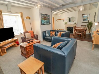A living room with blue leather sofas a brown armchair a wooden coffee table and a dining area at Woolley Lodge in Wooler
