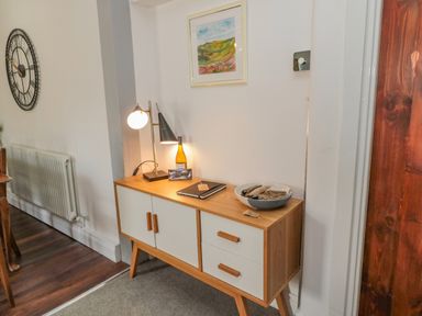 A wooden sideboard with two lamps a bottle a bowl with objects and a notebook in a room at Woolley Lodge in Wooler