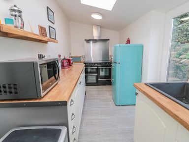 A kitchen with a microwave on wooden countertop a turquoise fridge a black oven and a sink at Woolley Lodge in Wooler