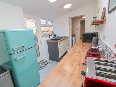 A kitchen with a turquoise fridge a wooden countertop and a sink at Woolley Lodge in Wooler