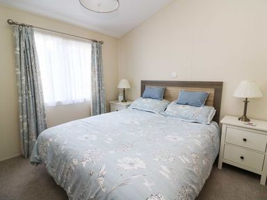 A bedroom with a double bed and two bedside tables with lamps at The Potting Shed in New Quay