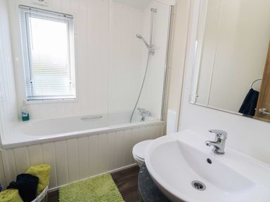 A bathroom with a bathtub shower sink mirror and towels at The Potting Shed in New Quay