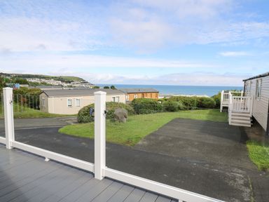 A view of mobile homes with a road grass and the sea in the background at The Potting Shed in New Quay