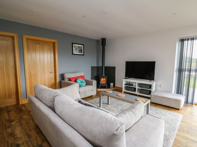 A living room with sofas a coffee table a wood stove and a television at Llyn Cae Ty Nant Fishery Holiday Let in Bwlchllan near Llangeitho