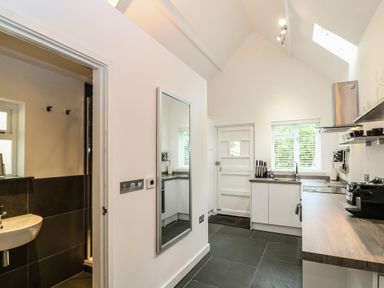 A kitchen with white cabinets a wooden countertop a sink a stove and a mirror on the wall at Twigs in Woody Bay