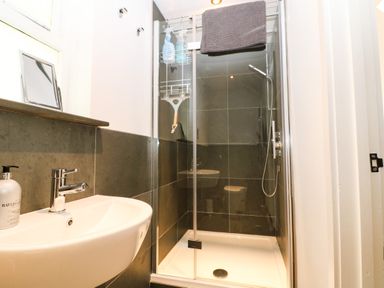 A bathroom with a wall-mounted sink and a glass-enclosed shower at Twigs in Woody Bay