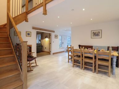 A dining area with wooden chairs and table near a staircase in a room at Merddwr in Cerrigydrudion