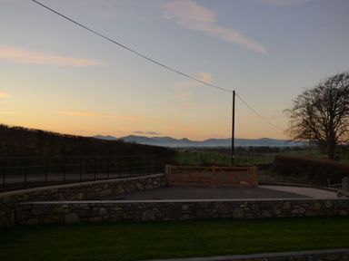 A rural landscape at sunset with a wooden gate stone walls and a tree at Merddwr in Cerrigydrudion