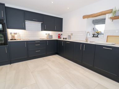 A kitchen with dark cabinets and a window at Merddwr in Cerrigydrudion