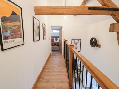 A hallway with wooden beams and artwork on the walls at Merddwr in Cerrigydrudion