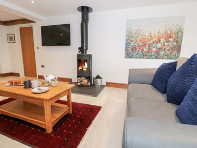 A living room with a wood stove and coffee table at Merddwr in Cerrigydrudion