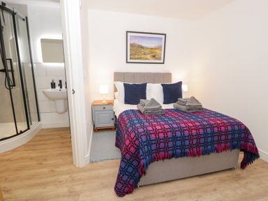 A bedroom with a bed and adjoining shower at Merddwr in Cerrigydrudion