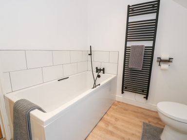 A bathroom featuring a bathtub, toilet, and towel rack at Merddwr in Cerrigydrudion