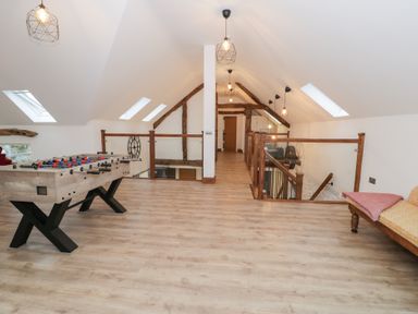 A games room with a foosball table and wooden beams at Merddwr in Cerrigydrudion