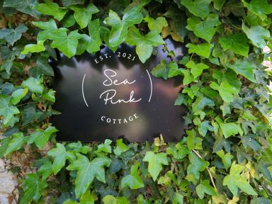 A sign for Sea Pink Cottage surrounded by ivy in Langton Matravers