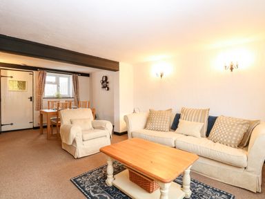 A living room with a sofa armchair wooden coffee table dining table and chairs at Phloxhaven in Reedham